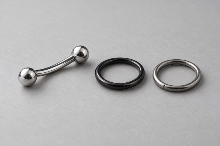 Gepolijste gebogen staaf, zwarte ring en zilverkleurige metalen ring op een lichte achtergrond