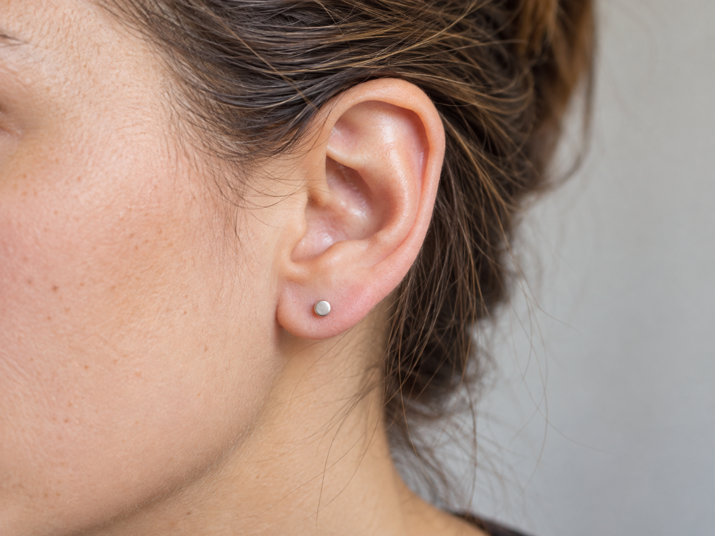 Orecchio con gioiello da piercing e segni neutri di guarigione stabilizzata.