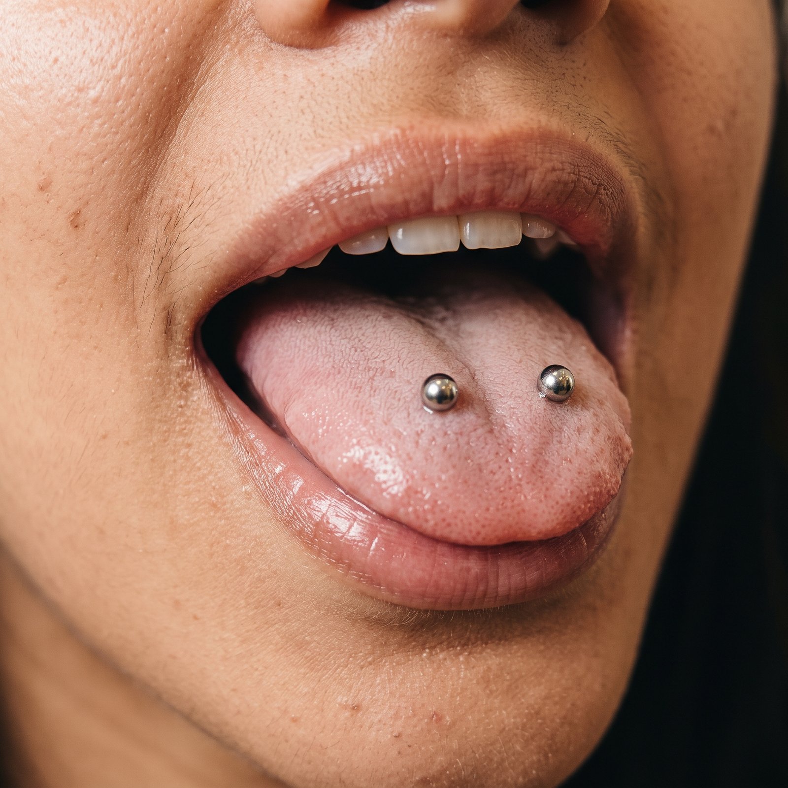Due piercing linguali verticali distinti, uno per lato, nella configurazione Venom