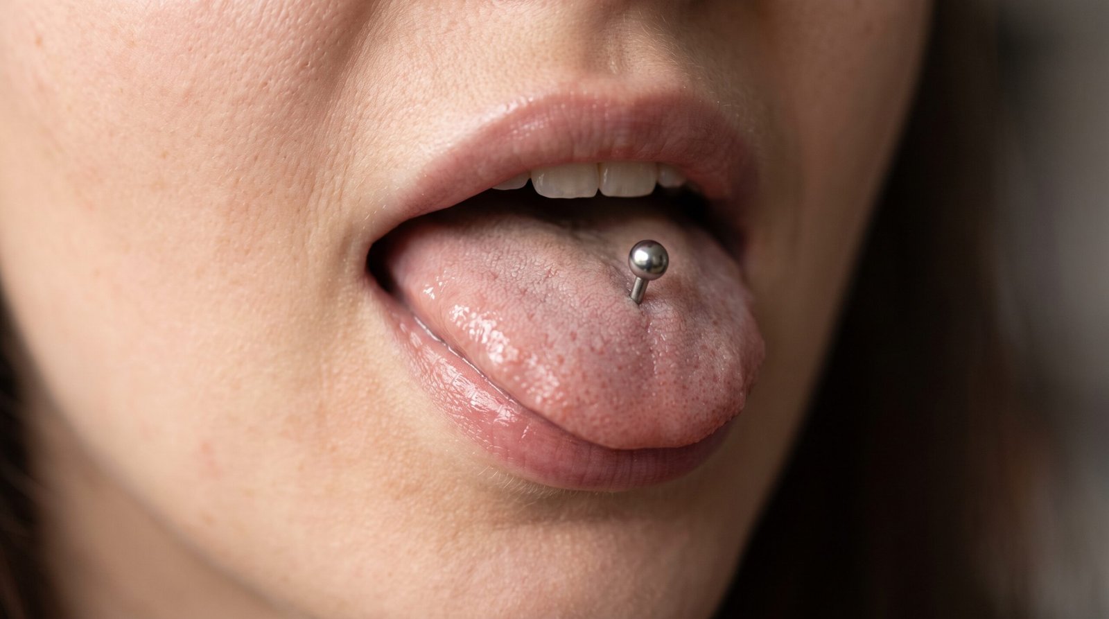 Piercing linguale tradizionale verticale con terminale a sfera, mostrato sulla lingua protrusa.